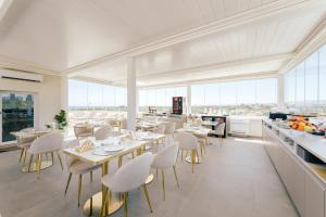 a restaurant with white tables and chairs and windows at Eleia Domos - Althea Homes in Monopoli