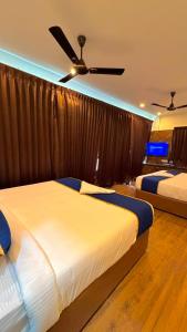 a bedroom with two beds and a ceiling fan at Hotel Vakula Matha Grand in Tirupati