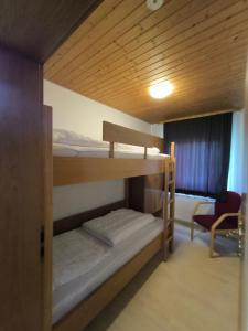 a bunk bed room with two bunk beds and a chair at Obergeschoss Bungalow 47 in der Ferienanlage RHÖN RESIDENCE in Dipperz