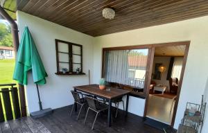 a patio with a table and a green umbrella at Obergeschoss Bungalow 47 in der Ferienanlage RHÖN RESIDENCE in Dipperz +21 photos