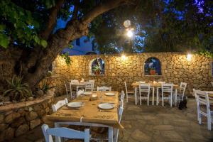 a restaurant with tables and white chairs and a stone wall at Perla Marina Hotel in Ialysos