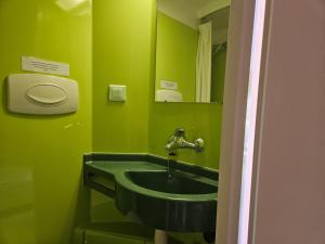 a green bathroom with a sink and a mirror at Villa des Familles La Bourboule in La Bourboule +41 photos