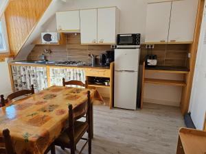 a kitchen with a table and a white refrigerator at Villa des Familles La Bourboule in La Bourboule