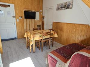 a room with a table with chairs and a television at Villa des Familles La Bourboule in La Bourboule
