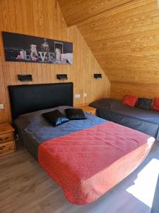 two beds in a room with wooden walls at Villa des Familles La Bourboule in La Bourboule