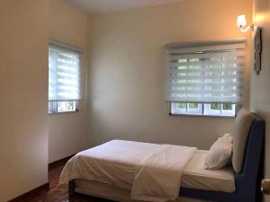 a bedroom with a bed and two windows at Cozy Modern Quiet Garden in Tanah Rata
