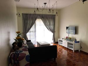 a living room with a couch and a tv at Cozy Modern Quiet Garden in Tanah Rata