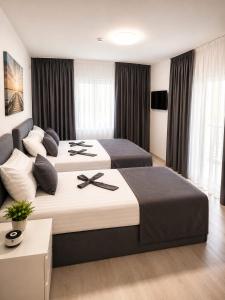 a hotel room with two beds with black crosses on them at Grey in Călimăneşti