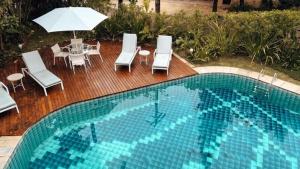 a pool with chairs and a table and an umbrella at Savay Hotel Boutique - Guarujá in Guarujá