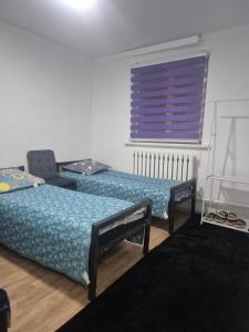 two beds in a room with a purple window at Nur Guest House 17 in Saty