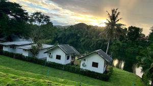 two white houses on a hill next to a river at ริมแควโฮมสเตย์ กาญจนบุรี in Ban Pong Pat