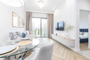 a white living room with a glass table and chairs at Olsztyn Kapitańska 2 in Olsztyn