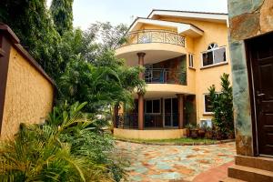 ein großes gelbes Haus mit einem Balkon auf dem Dach in der Unterkunft Midindi Hotel in Accra