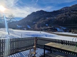 a bench sitting on a fence with a snow covered field at Ferienhaus mit Bergblick am Wald in Stall