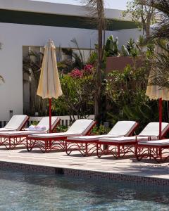 a row of lounge chairs and an umbrella next to a swimming pool at Good Days Caesar in Ras Elhekma