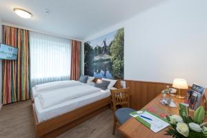 a bedroom with a bed and a table and a desk at Hotel Westfalia in Bremen