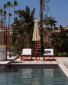 two chairs and an umbrella next to a swimming pool at Good Days Caesar in Ras Elhekma