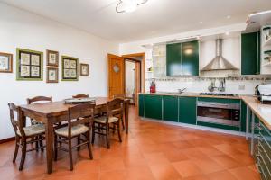 a kitchen with green cabinets and a wooden table and chairs at Casa Aldrovandi in Capoliveri