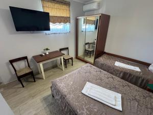 a room with two beds and a table and a television at Готель Пісня Гір in Ralevka