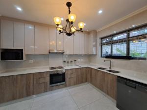 a kitchen with white cabinets and a chandelier at Moxley Manor in Durban