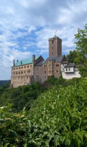 an old castle on top of a hill with vegetation at Traumzeit-Ferienwohnung in Eisenach