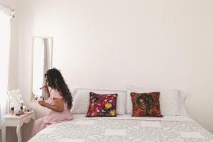 a woman standing in front of a bed looking in a mirror at Casa Viveros cerca de jardines 3 recamaras albercas y 2 estacionamientos in Jiutepec