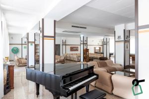 a black piano in a living room with couches at Hotiday Vieste Centro in Vieste
