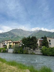 a river with buildings and mountains in the background at Alpine penthouse, breathtaking views! in Bussoleno