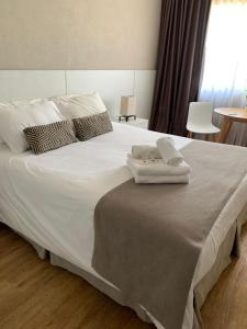 ein großes weißes Bett mit zwei Handtüchern darauf in der Unterkunft Hotel Flores in Trinidad