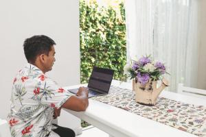 a man sitting at a table with a laptop at Casa Viveros cerca de jardines 3 recamaras albercas y 2 estacionamientos in Jiutepec