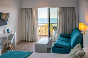 a living room with a blue couch and a view of the ocean at Hotel Pinos Playa in Cala Santanyi