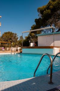 a swimming pool with blue water at Hotel Pinos Playa in Cala Santanyi