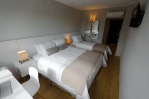 ein Hotelzimmer mit zwei Betten und einem Fernseher in der Unterkunft Hotel Flores in Trinidad