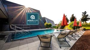 a pool with chairs and umbrellas in front of a building at Das Karl August in Fohnsdorf