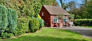 a red brick house with a patio and a yard at Studio Lodge in Crowhurst