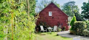 a red barn with a table and chairs in a yard at Studio Lodge in Crowhurst