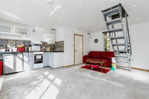 a living room with a red couch and a kitchen at Studio Lodge in Crowhurst