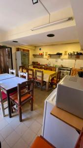 a dining room with tables and chairs and a kitchen at Hostel Maranata in Puerto Madryn