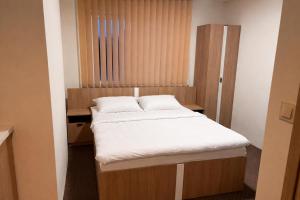 a small bedroom with a bed with white sheets at Aura Pokoje na Wynajem in Wojnicz