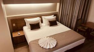 a hotel room with a large bed with a pillow on it at Actuall Convention Hotel in Contagem