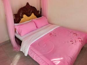 a pink bed with a wooden headboard and pink sheets at JA Haven Suite in Lira