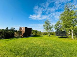 a large grass field with a building in the background at Kadaksalu with sauna hinnas in Ruu +17 photos