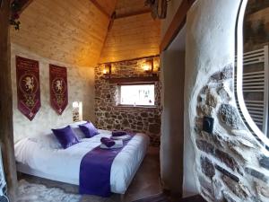 a bed in a room with a stone wall at La Synchronicité - Chambres d'Hôtes in Vaudrimesnil