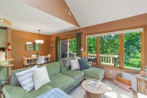 a living room with a green couch and a table at King Bed Fire Pit Pool & Walk to North Course in Galena