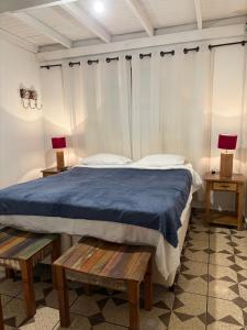 a bedroom with a bed with blue sheets and two tables at Aconchego Central in Tiradentes