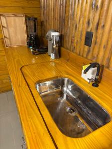 a kitchen counter with a stainless steel sink at Chalé Suíco Vale do Capão in Palmeiras +25 photos