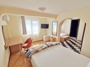 a hotel room with a bed and a desk and a bedroom at Hotel VALDI in Ahtopol