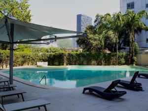 ein Swimmingpool mit zwei Liegestühlen und einem Sonnenschirm in der Unterkunft Novotel Monterrey Valle in Monterrey + 226 Fotos
