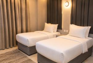 two beds in a hotel room with white sheets at Areen Al Naeem Served Apartments in Jeddah +21 photos
