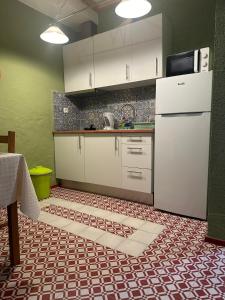 a kitchen with white cabinets and a white refrigerator at Casa tio Manuel in São Martinho das Amoreiras